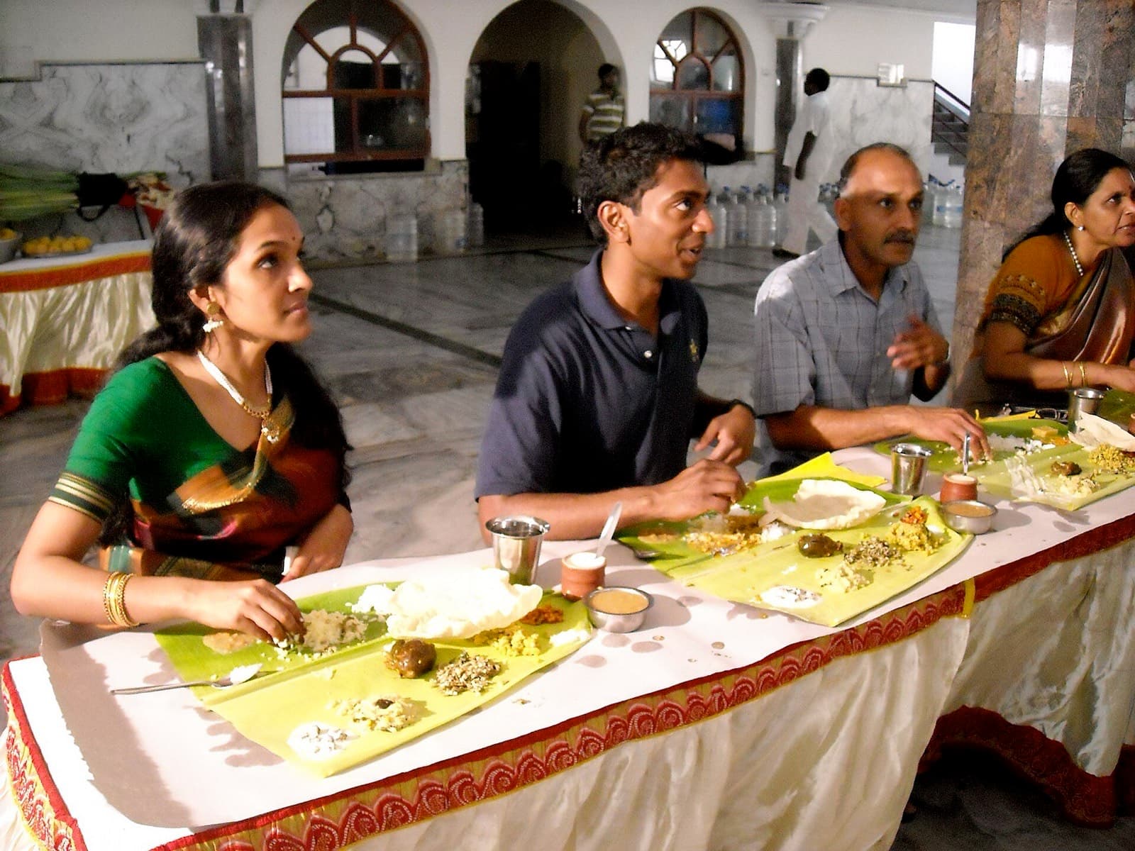 Guests eating a vegetarian lunch from banana leaves at a wedding hall