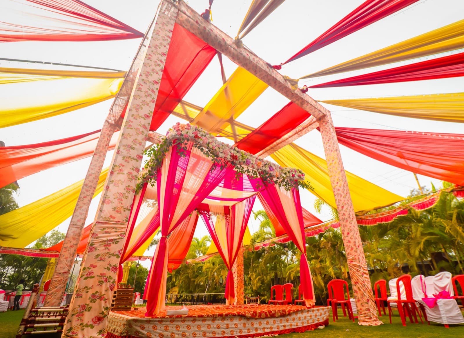 A decorated mandap with magenta drapes and flower garlands